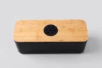 Black cable management box with bamboo lid hiding a power strip, front view