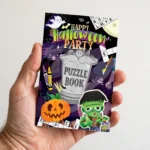 Hand holding the Halloween A6 puzzle book showing pocket-size scale