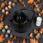 Flat lay of the black cauldron oil burner with wax melts and dried autumn flowers