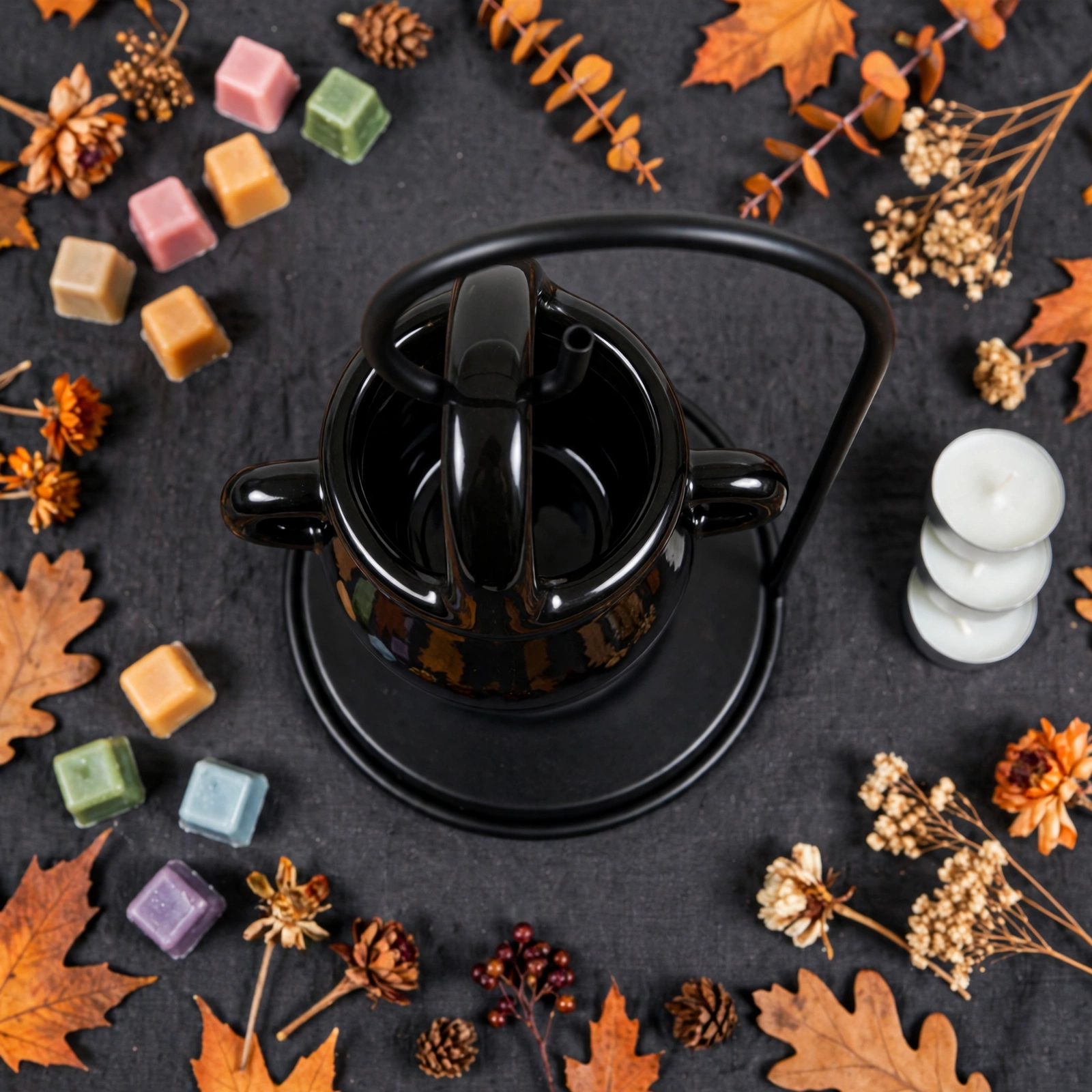 Black cauldron oil burner styled with wax melts and dried autumn flowers