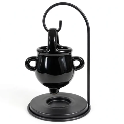 Black ceramic witch cauldron oil burner hanging on a metal stand, front studio view