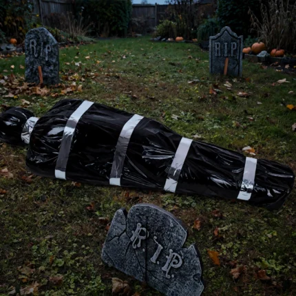 Fake corpse prop in a garden graveyard scene with tombstones at dusk