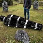 Person kneeling beside the fake corpse prop to show its life-size scale