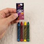 Hand holding a Halloween mini wax crayon pack to show its small size