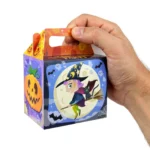 Hand holding a Halloween party treat box showing its handy size