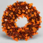 Orange and black Halloween tinsel door wreath with pumpkin cut-outs, front view