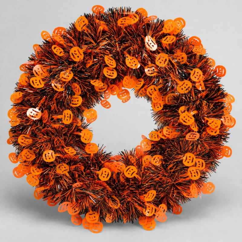 Orange and black Halloween tinsel door wreath with pumpkin cut-outs, front view