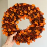 Hand holding the Halloween tinsel wreath to show its generous size