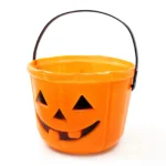 Orange pumpkin Halloween candy bucket with wire handle, three-quarter angle view