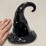 Hand next to the witch hat tealight holder showing its size
